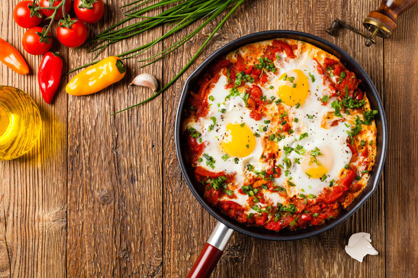 Shakshouka, dish of eggs poached in a sauce of tomatoes, chili peppers, onions. Top view.  - Foto, Imagen