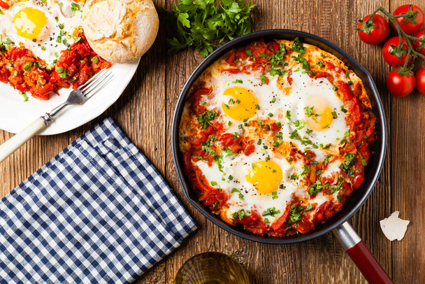 Shakshouka, dish of eggs poached in a sauce of tomatoes, chili peppers, onions. Top view.  - Фото, изображение