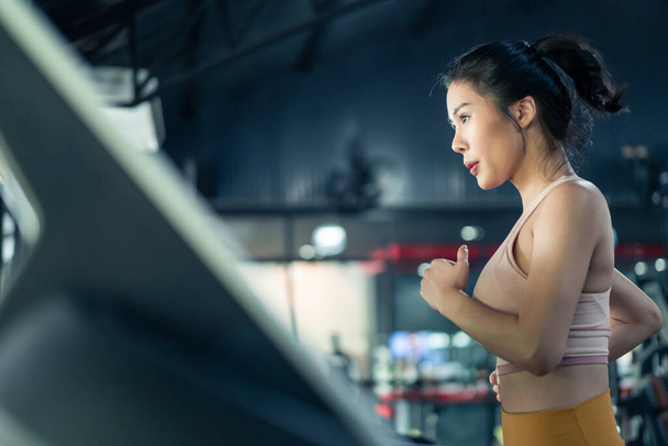 Aziatische jonge atleet sportvrouw praktijk workout om spier te behouden in de sportschool of fitnessclub. Actief aantrekkelijk meisje in sport slijtage oefening door te lopen op loopband om calorieën te verbranden voor de gezondheid in het stadion - Foto, afbeelding