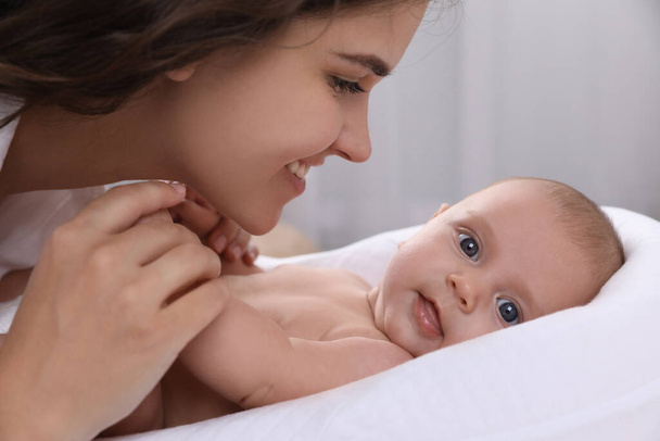 Happy young mother with her cute baby on bed at home, closeup - Foto, Imagen