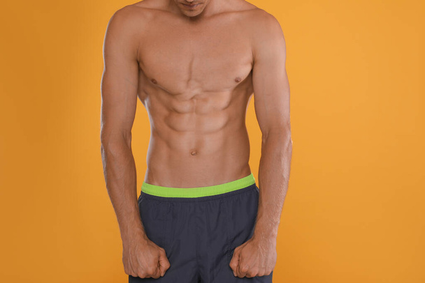 Shirtless man with slim body on yellow background, closeup - Фото, зображення
