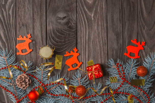 Christmas decoration with fir branches and red christmas balls on dark wooden background with copy space - Photo, Image