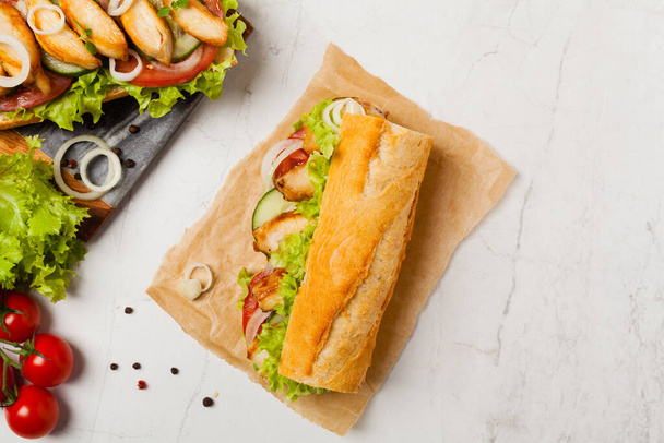 Chicken sandwich with tomato, cucumber, lettuce and onions. White stone background. Top view. Flat lay. - Φωτογραφία, εικόνα