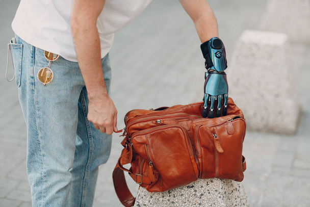 Jonge gehandicapte man met kunstmatige prothetische hand in casual kleding. - Foto, afbeelding
