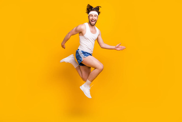 Full length body size view of attractive cheerful carefree guy jumping running isolated over bright yellow color background - Zdjęcie, obraz