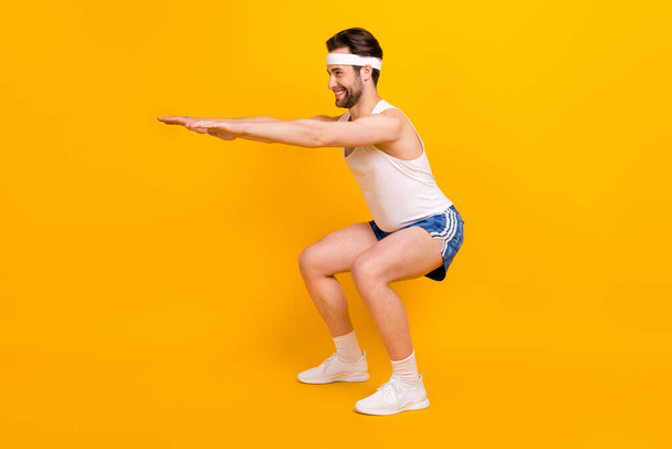 Full length body size profile side view of attractive cheerful guy doing sit-ups pilates isolated over bright yellow color background - Фото, изображение