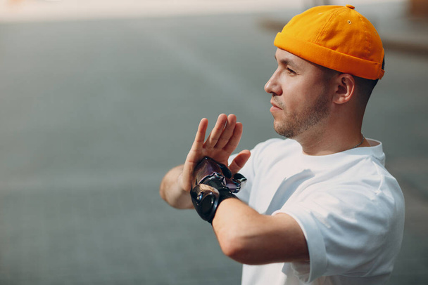 Junger behinderter Mann mit künstlicher Handprothese beim Yoga-Asana in lässiger Kleidung auf der Straße der Stadt. - Foto, Bild