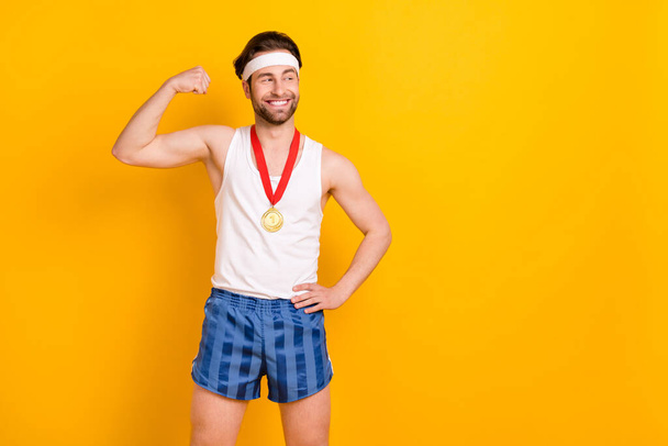 Portrait of attractive cheerful content guy leader demonstrating muscles copy space isolated over bright yellow color background - Fotó, kép
