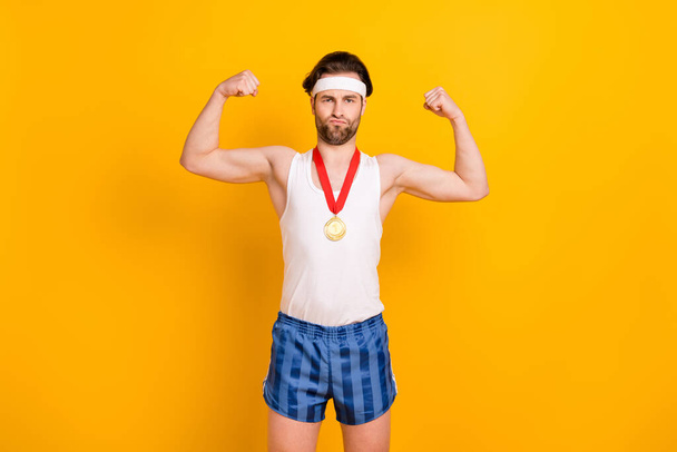 Portrait of attractive funny confident guy leader demonstrating muscles isolated over bright yellow color background - Photo, Image