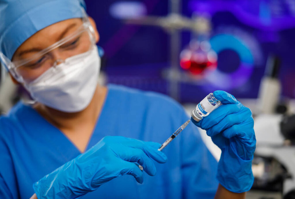 Ärzte in blauer Uniformkleidung tragen Gesichtshygienemaske, halten Impfflasche und stecken Nadel hinein, arbeiten im Labor. - Foto, Bild