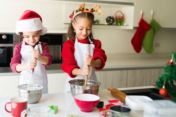 Lindos irmãos bonitos misturando a massa de biscoito e açúcar gelado enquanto se divertem juntos em uma cozinha de Natal - Foto, Imagem