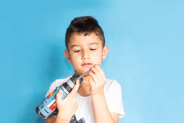 boy holds a screwdriver on a blue background. A student studies the work of tools - Photo, image
