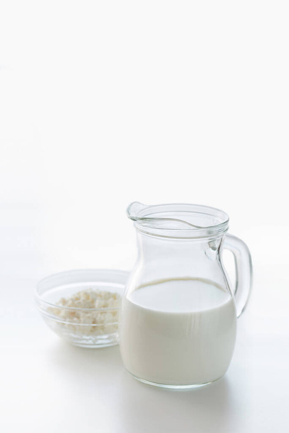 Milk in a jug and cottage cheese in a bowl on a light background with copy space - Foto, immagini