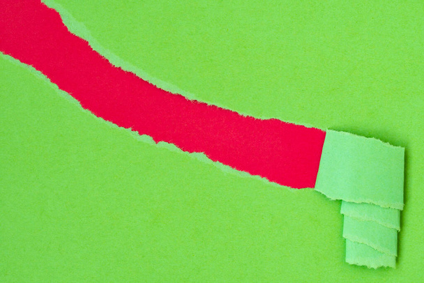 Hole torn in green paper background to reveal hidden copy-space underneath - Foto, Imagen