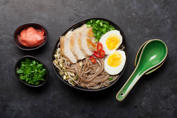 Zuppa di ramen di noodle asiatico con pollo, verdure e uova su sfondo di pietra. Vista dall'alto piatto lay
 - Foto, immagini