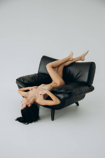 naakt mooi brunette meisje op een naakt foto sessie in een foto studio poseren op een fauteuil en onder de douche - Foto, afbeelding