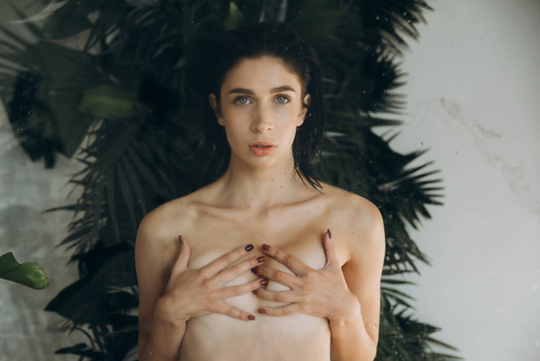 Nudo bella ragazza bruna in una sessione di foto nude in uno studio fotografico, in posa su una poltrona e sotto la doccia - Foto, immagini
