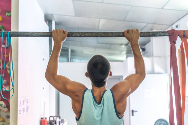Athlete exercising on the gym's horizontal bar practicing calisthenics. Handsome man doing functional training. Healthy and wellness concept. - Φωτογραφία, εικόνα