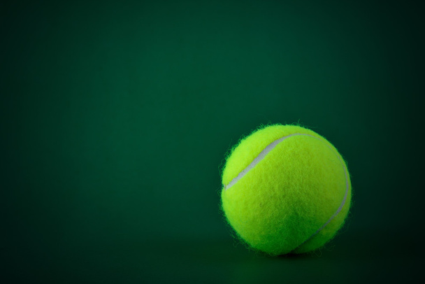 Один теннисный мяч на зеленом фоне
 - Фото, изображение