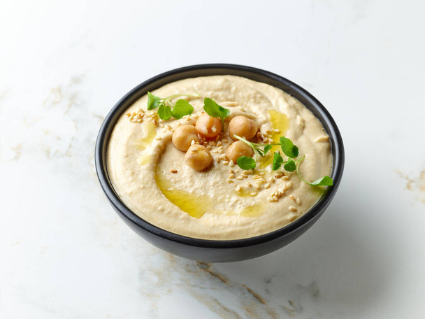 bowl of hummus on kitchen table - Фото, изображение