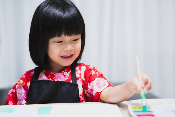 Confiance positivité et liberté être concept créatif. Portrait d'une adorable petite fille asiatique tenant un pinceau et faisant sur une peinture pour classe d'art à l'école. Enfant de 4-5 ans. - Photo, image