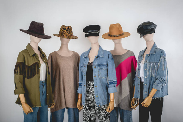 Beautiful five mannequins dressed with stylish and fashion clothes (jackets, sweaters, pants, shirts) and hats in white background - Photo, Image