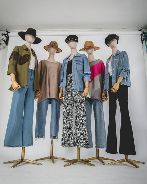 Beautiful five mannequins dressed with stylish and fashion clothes (jackets, sweaters, pants, shirts) and hats in white background - Фото, зображення