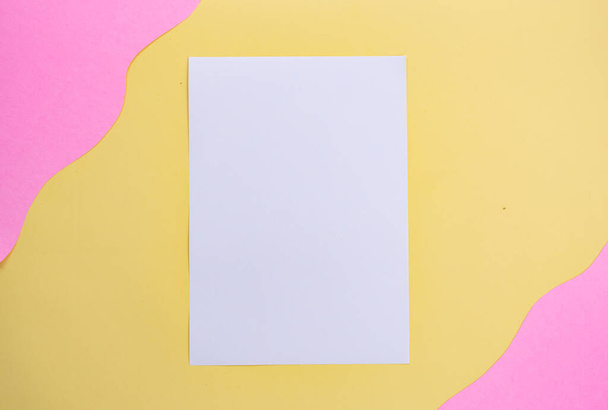 белая бумага на желтом и розовом фоне. минималистский стиль - Фото, изображение