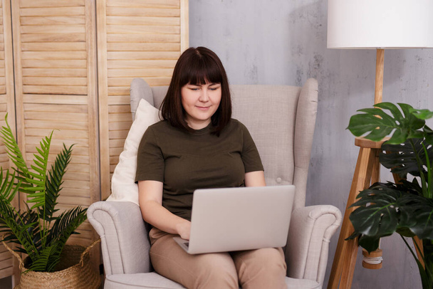 Happy brunette woman using laptop at cozy home - Photo, Image