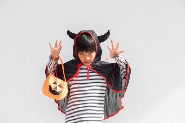 Hauska halloween lapsi käsite, pieni söpö tyttö puku halloween aave pelottava hän pitää oranssi kurpitsa aave käsillä, valkoisella taustalla  - Valokuva, kuva