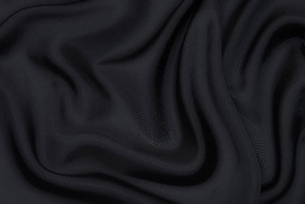 Black fabric texture background, wavy fabric slippery black color, luxury satin or silk or wool cloth texture. - Photo, Image