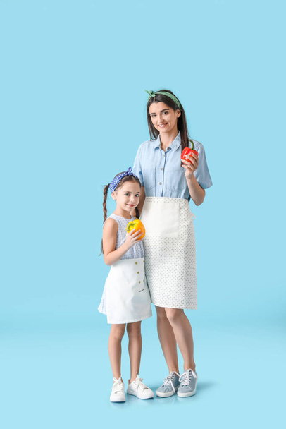 Junge Mutter und Tochter mit frischen Paprika auf farbigem Hintergrund - Foto, Bild