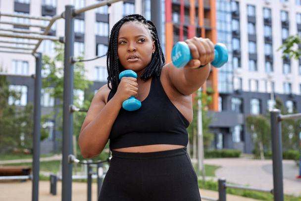 Portrait of young confident african woman exercising with dumbbells - Photo, image