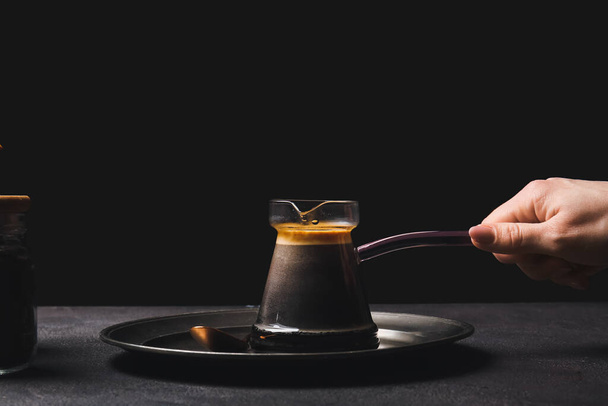 Mujer con delicioso café turco en cezve sobre fondo oscuro - Foto, Imagen