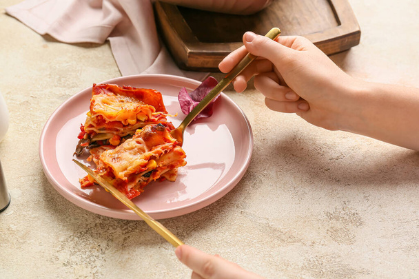 Woman eating delicious lasagna with tomato sauce on light table - Photo, Image