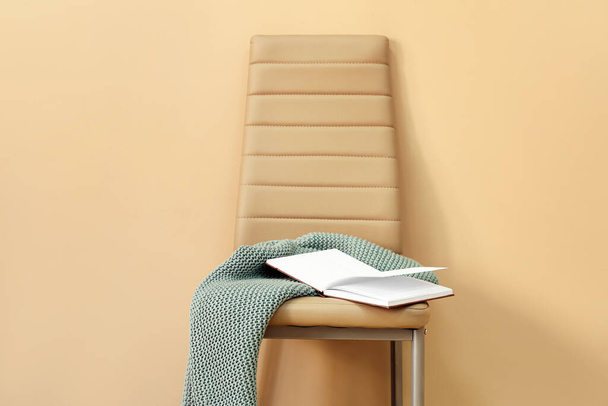 Chaise avec plaid et livre ouvert près du mur de couleur - Photo, image