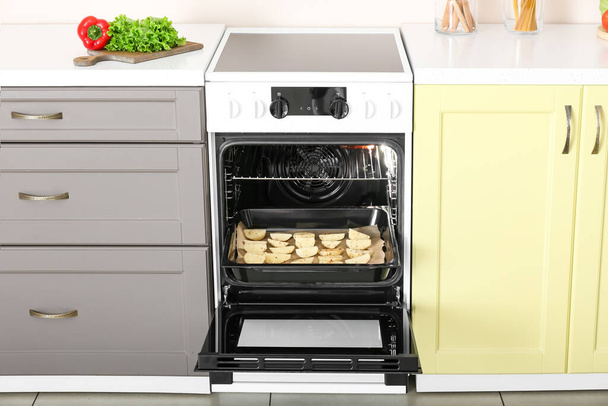 Electric oven with potato in kitchen - Photo, Image