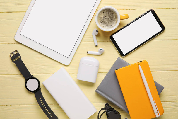 Διαφορετικές σύγχρονες συσκευές, φλιτζάνι καφέ και σημειωματάρια σε ξύλινο φόντο χρώμα - Φωτογραφία, εικόνα