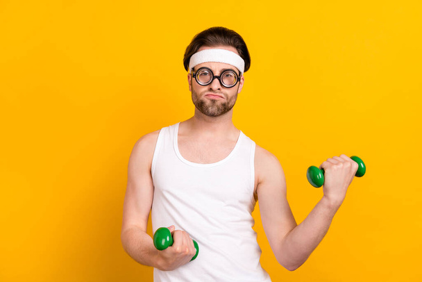 Portrait of attractive funky guy nerd doing work out muscles development isolated over bright yellow color background - Foto, immagini