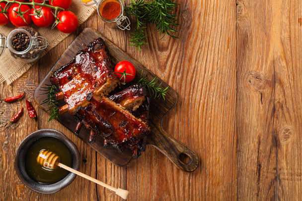 Roasted pork ribs in a bbq sauce. Served on a wooden board. Top view. - Valokuva, kuva