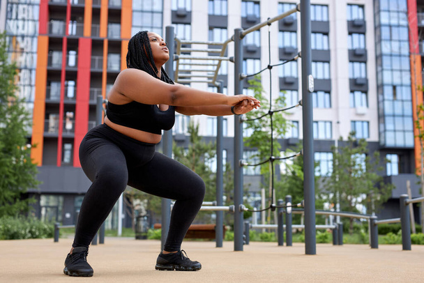Physical exercise squat for fitness performed by obese african young woman - Foto, imagen