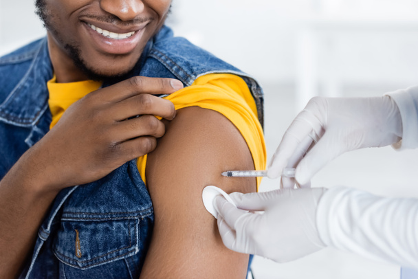 vue recadrée de l'infirmière qui injecte le vaccin à un homme afro-américain souriant - Photo, image