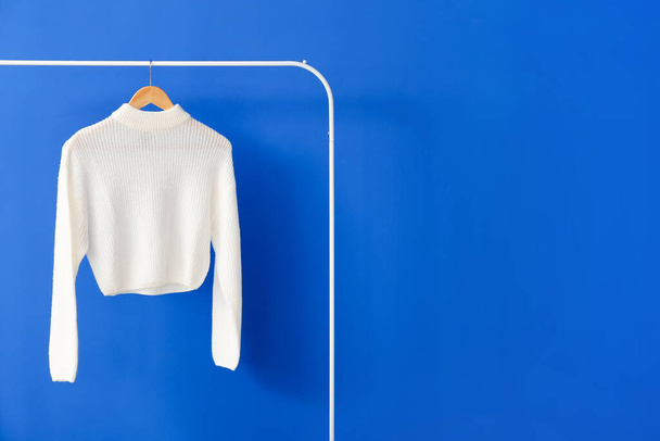 Rack with knitted sweater on color background - Φωτογραφία, εικόνα