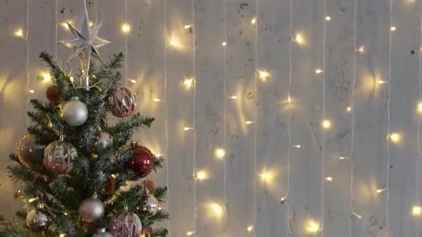 decorated christmas tree over grey wall with festive lights - Footage, Video