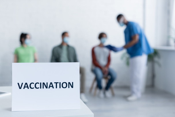 πινακίδα πλάκα με γράμματα εμβολιασμού κοντά θολή αφροαμερικανός γιατρός και ασθενείς - Φωτογραφία, εικόνα