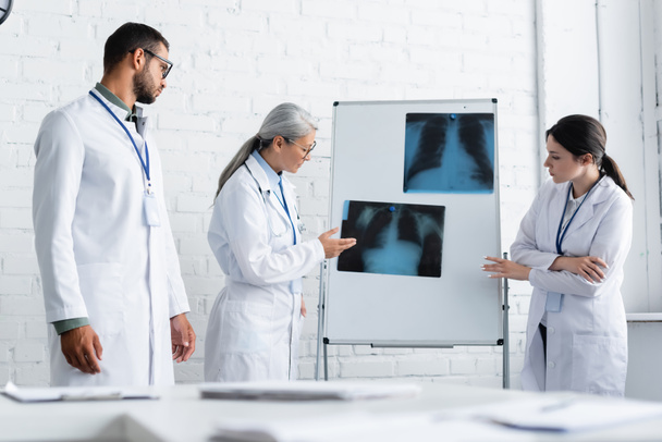 mature asian doctor pointing at lungs x-ray on flip chart near young colleagues - Fotografie, Obrázek