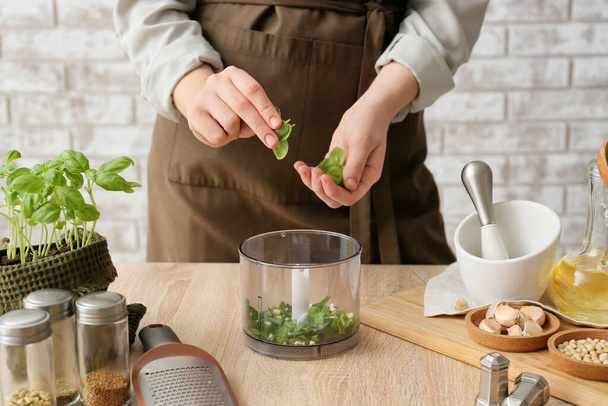 Mujer preparando sabrosa salsa de pesto en la mesa - Foto, Imagen
