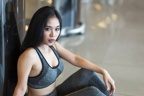 Fitness Asian women sitting in sport gym interior and fitness health club with sports exercise equipment Gym background. - Photo, Image