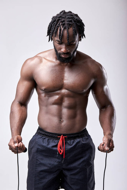 Half-naked sweaty african man holding skipping rope in hands, preparing to jump - Foto, Imagem