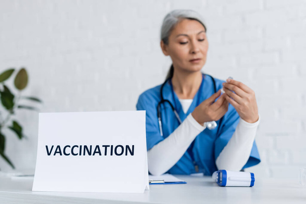 maduro asiático médico celebración tarro con vacuna cerca tarjeta con vacunación lettering - Foto, Imagen